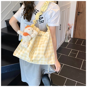 Detail of yellow checkered bag with ruffled strap and a cute plush dog pendant