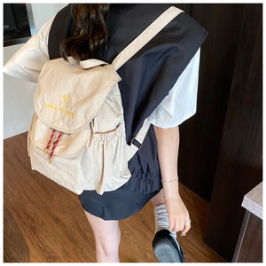 Dettaglio dello zaino in tela beige con ricamo take it easy e coulisse a strisce