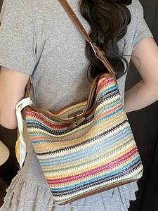 Colorful striped woven straw tote bag with brown leather straps shown on model back