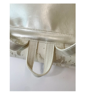 Close-up of top handle and reinforced stitching on the silver butterfly backpack