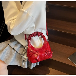 Detail of red glossy bow handbag with ruffled handle and silver star charm on stairs
