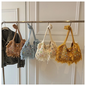 Close-up of knit tote bags in multiple colors with pearl buttons and fringe details