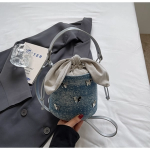 Détail du sac seau en jean bleu avec papillons argentés et cordon en nœud de tissu