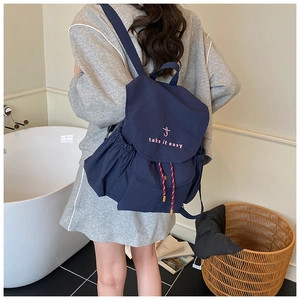 Dettaglio dello zaino in nylon blu navy con ricamo rosa e tasca laterale esterna