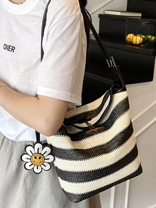 Straw tote bag with black and white stripes featuring toggle closure and daisy charm