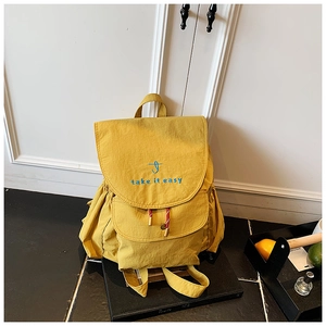 Dettaglio dello zaino giallo in tela con ricamo blu e tasche laterali con coulisse
