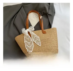 Detail of hand-woven straw tote with brown leather handle and white lace bow decoration