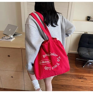 Close-up of bright red drawstring tote bag featuring white graphic lettering in a home setting