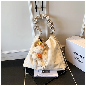 Detail of cream checkered tote bag with ruffled handle and plush bunny charm