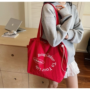 Detail of red canvas tote bag with 'Bring Color To Your Life' print and side drawstring