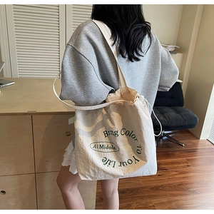 Detail of beige canvas tote bag with green Bring Color To Your Life text print