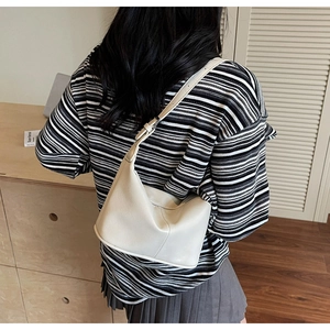 Vue de dos d'un mannequin portant un sac à bandoulière en cuir crème de style minimaliste