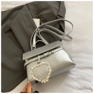 Silver metallic handbag with wrinkled texture and lace heart charm on grey suit