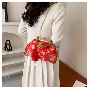 Detail of red floral embroidery on satin shell bag with bamboo handle and gold chain