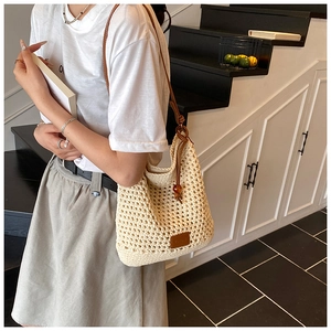 Detail of woven crochet tote bag with brown leather strap and wooden bead decoration