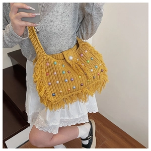 Détail du sac en tricot jaune avec perles colorées et pompons décoratifs à franges