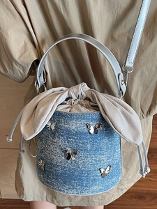 Sac seau en denim bleu avec papillons argentés et fermeture à nœud coulissant