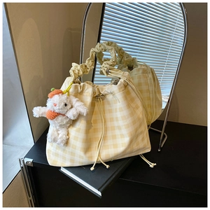 Detail of yellow gingham drawstring bag with ruffled handle and plush bunny pendant