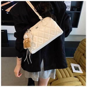 Detail of white quilted bowling bag with a cute brown bear charm on the shoulder strap