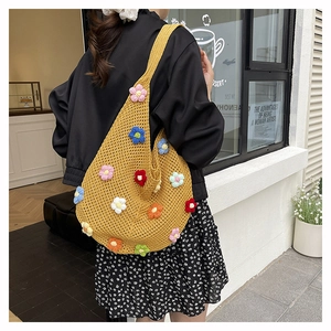 Détail d'un sac cabas en tricot jaune avec fleurs 3D colorées et texture tressée