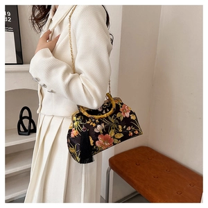 Detail of floral silk handbag with bamboo handle and gold chain strap on model