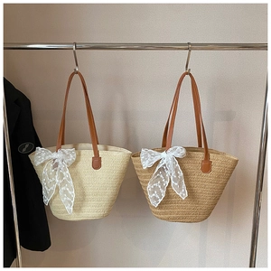 Detailed close-up of woven straw tote bags with lace bow accents and brown leather handles