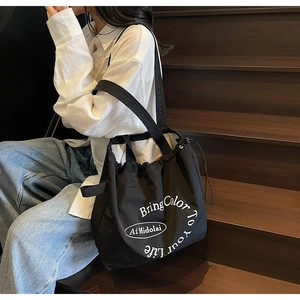 Detail view of black drawstring tote bag with white slogan Bring Color To Your Life