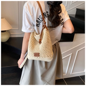 Detail of woven mesh tote bag with brown leather straps and brand logo for beach vacations