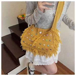 Close-up of bright yellow crochet tote bag with colorful acrylic beads and fringe details