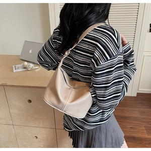 Sac hobo beige minimaliste sur l'épaule d'un mannequin dans un intérieur élégant