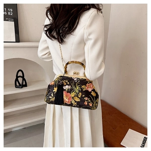 Detailed view of retro floral satin handbag with bamboo handle and black tassels