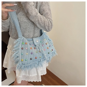 Détail d'un sac à bandoulière en crochet bleu clair avec perles colorées et pompons