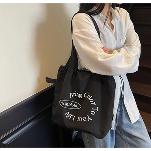 Detail of black canvas tote bag with white circular text and drawstring closure