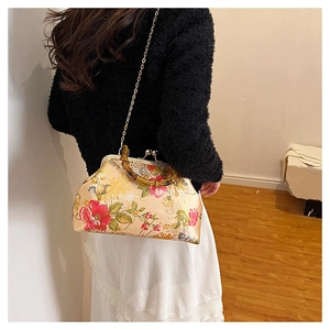 Detail of vintage floral silk handbag with bamboo handle and golden chain strap