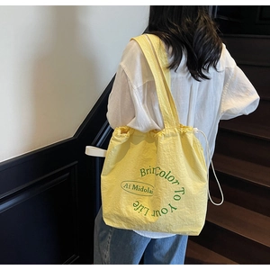 Detail of yellow canvas shoulder bag with drawstring and Bright Color To Your Life slogan