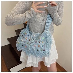 Détail du sac tricoté bleu clair avec perles colorées, grande perle et longues franges