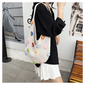 Detail of hand-woven off-white crochet tote bag with colorful 3D knitted flower accents