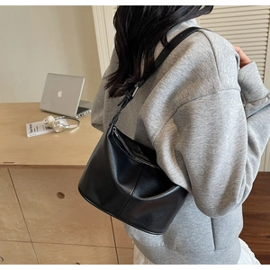 Vue latérale d'un sac à bandoulière noir en demi-lune dans un cadre de bureau quotidien