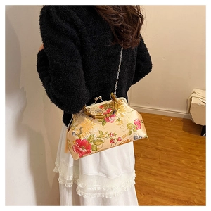 Macro detail of silk floral embroidery on vintage handbag with bamboo handle