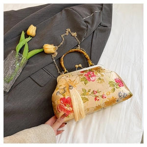 Detailed shot of beige satin floral bag with bamboo handle and elegant silk tassel detail