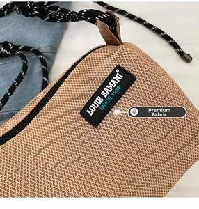 Close-up of premium khaki mesh fabric and black logo patch on casual crossbody bag