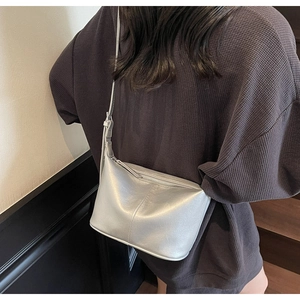 Détail du sac à bandoulière en similicuir argenté avec finition métallique sur modèle