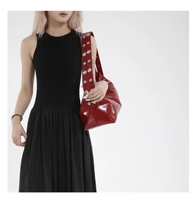 Détail du sac croissant en cuir ciré rouge avec large bandoulière à rivets argentés