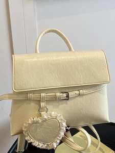 Sac à dos chic en cuir beige grainé avec breloque cœur en dentelle et rabat à boucle