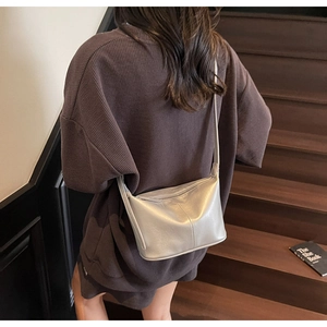 Détail du sac à bandoulière argenté en similicuir souple porté sur l'épaule