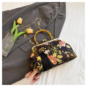 Detailed view of floral embroidery on black satin bag with bamboo handle and silk tassel