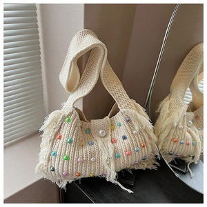Détail de la texture tricotée avec perles colorées et franges sur un sac au crochet blanc
