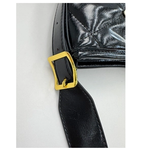 Détail d'un sac en cuir matelassé noir avec une boucle métallique dorée élégante