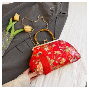 Detail of red floral silk handbag with bamboo handle, gold chain and tassel