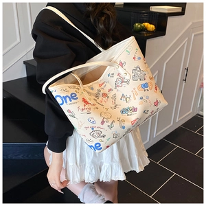 Close-up of cream canvas tote bag with colorful cartoon graffiti and leather straps